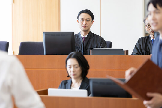 法廷で弁論を聞く裁判官と書記官の審理風景