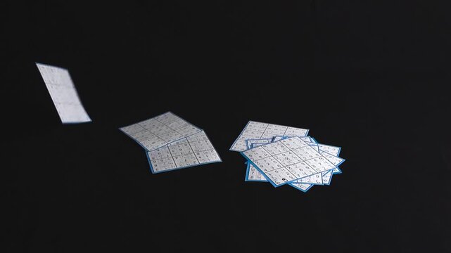 Many solved paper Sudoku puzzles are falling in slow motion against a solid black background, representing concepts of problem solving, logic, intelligence, and cognitive abilities