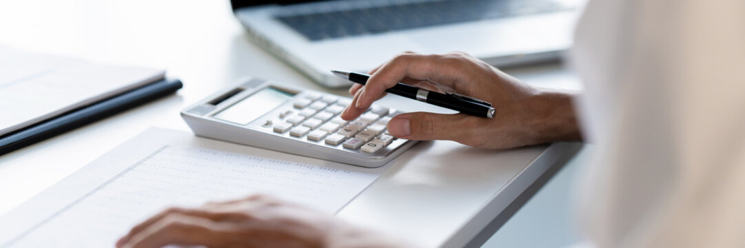 accountant using calculator and reviewing charts for tax adjustment on corporate financial document