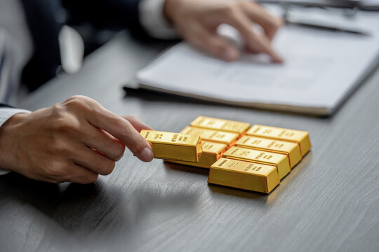 A hand holds a gold bar for financial success and investment strategy