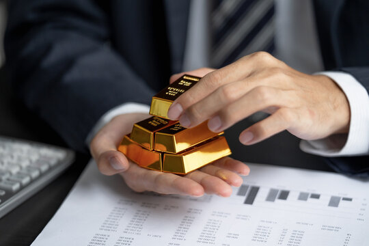 A hand holds a gold bar for financial success and investment strategy