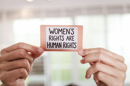 Hands holding a small sign with the message women's rights are human rights, equality, activism, and social justice.