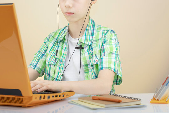 Schoolboy Studying on Laptop with Earphones at Desk, for Back to School Campaigns, Distance Learning, Online Education, Homework, Digital Learning, and Student Success