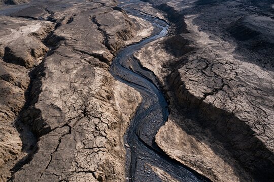 Polluted river flowing through dry cracked land