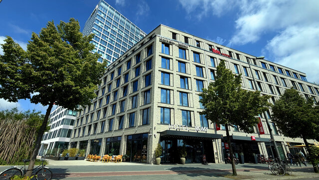Modern hotel Romy building with large glass windows and outdoor seating area, bicycles parked along the sidewalk in an urban setting