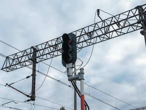 A railway signal light mounted on a steel gantry under a cloudy sky, controlling train movement and ensuring safety in a modern industrial transport infrastructure travel network system