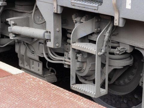 A close view of a metal access ladder attached to a heavy industrial train bogie, emphasizing railway maintenance engineering and the robust mechanical design of transit systems