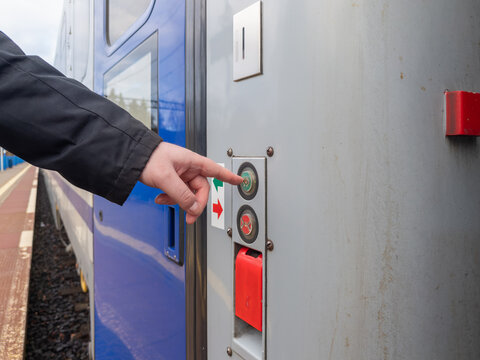 A passenger hand pushes the green open door button on a modern train carriage at a station platform, highlighting travel convenience, rail transit mobility and efficient boarding