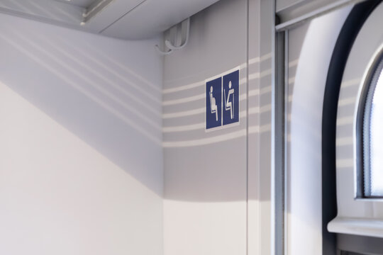 A blue priority seat sign displayed on the white wall inside a modern public train, representing accessibility and inclusive design for passengers with limited mobility or needs