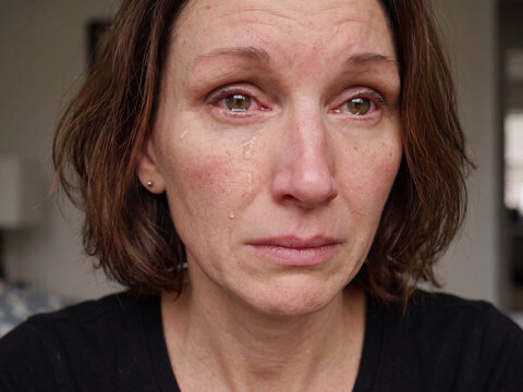 Portrait einer weinenden dunkelhaarigen Frau, die Augen geschwollen und ger&ouml;tet. Tr&auml;nen laufen &uuml;ber ihr Gesicht. 
