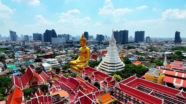 Aerial orbit shot circling around Giant Golden Buddha statue and white pagoda at Wat Paknam, Bangkok, Thailand