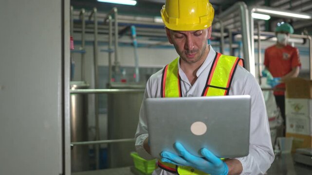 Engineer using laptop to monitor chia seed fruit juice production machinery in automated beverage factory system