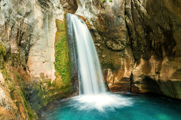 Serene waterfall cascading into a turquoise canyon pool. Long exposure nature photography for travel and environmental themes © serebryannikov
