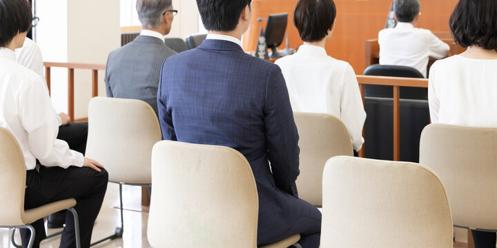 法廷で傍聴する人々の後ろ姿