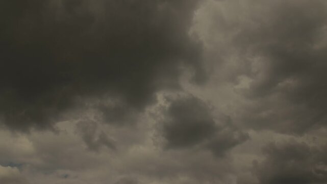 Timelapse of dense gray storm clouds gathering and covering the daytime sky