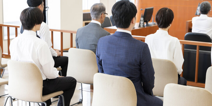 法廷で傍聴する人々の後ろ姿