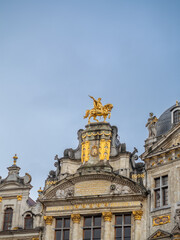 Obraz premium Ornate Baroque guild house facade with gilded decoration at the historic Grand Place under dramatic cloudy sky