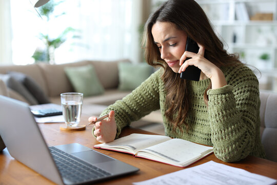 Stressed teleworker talking on phone checking agenda