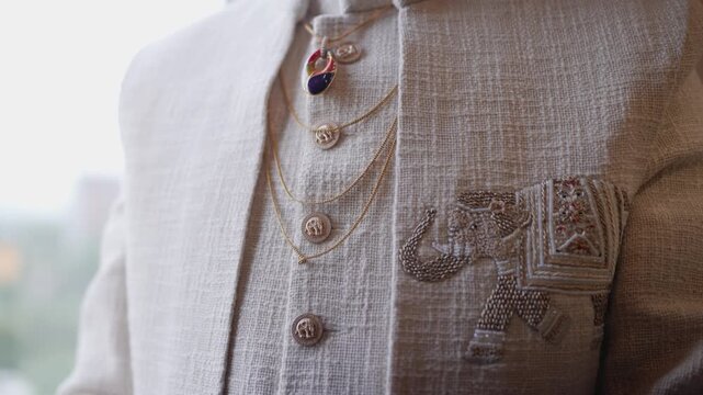 Detail shot of Indian groom's wedding attire, showcasing elegant elephant embroidery and traditional golden necklace chains