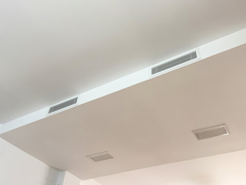 Linear slot diffusers of a ducted air conditioning system in a white ceiling bulkhead. Concealed home ventilation