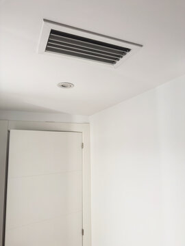 A rectangular air conditioning grille in a white ceiling bulkhead above a door. Ducted HVAC ventilation in an apartment