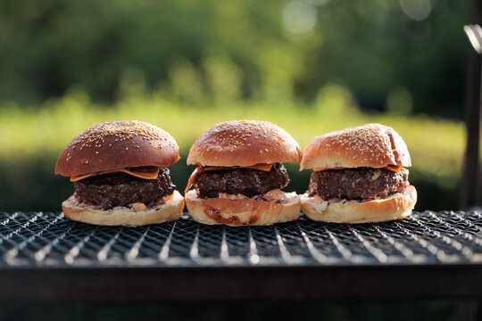 Cheeseburgers cooking on grill at outdoor barbecue