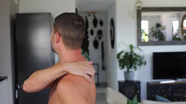 Man applying heating patch to relieve severe shoulder blade and back pain