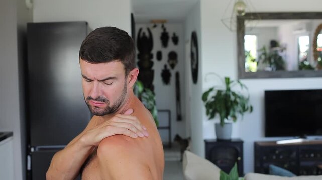 Man applying heating patch to relieve severe shoulder blade and back pain