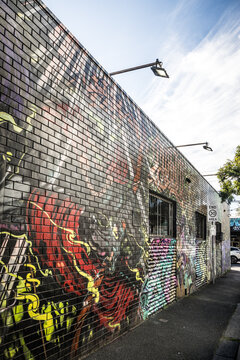Vibrant street art murals adorn brick wall in Melbournes Fitzroy district on a sunny afternoon