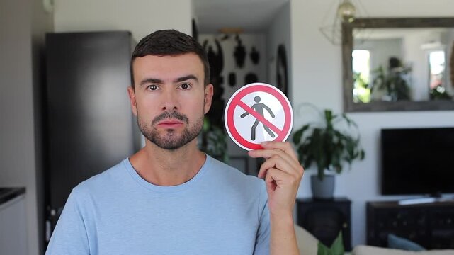 Man showing sign that tells people to not to enter somewhere