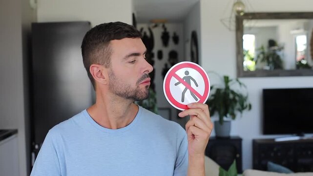 Man seriously showing forbidden sign with person icon direct to camera holding it as a warning against access