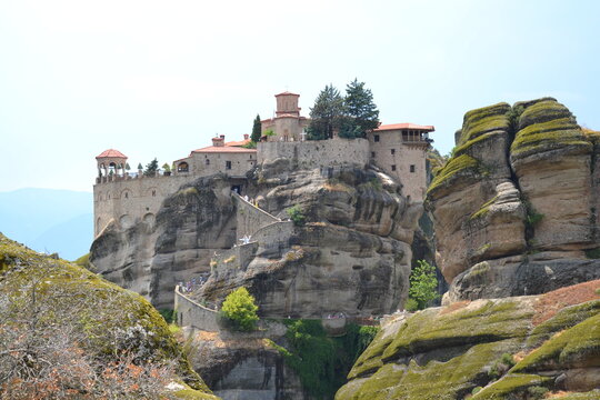 Stunning view of Varlaam Monastery perched on towering sandstone cliffs in Meteora, Greece. A UNESCO World Heritage Site surrounded by dramatic rock formations and breathtaking mountain scenery.