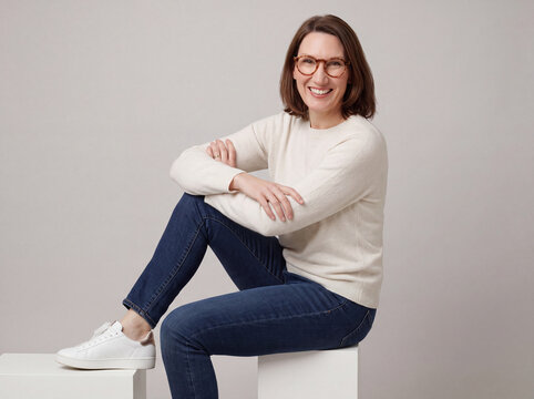 Business Portrait einer dunkelhaarigen Frau, leger gekleidet mit Jeans und Turnschuhen. 