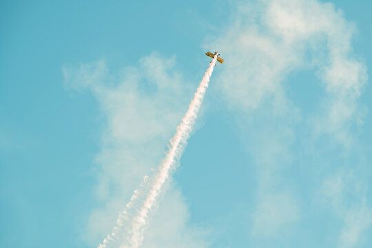 Portugal Oeiras Air Show. A plane flies high in the sky, making a sharp turn while leaving smoke trails behind. This event takes place during an air show near the city on a clear day.
