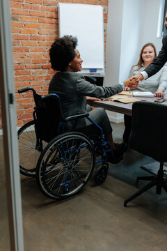Disabled businesswoman in wheelchair shaking hands in office