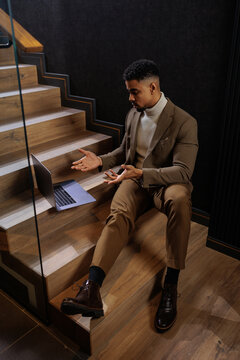 Businessman sitting on stairs reacting to laptop