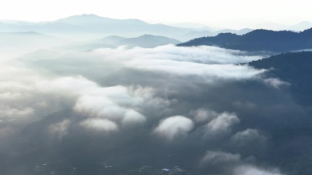 Aerial view of the mountainous highlands in Lam Dong, Vietnam, featuring lush green forests, rolling hills, valleys, and distant morning mist.