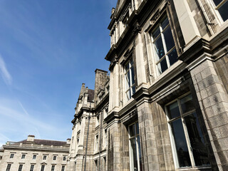 Obraz premium Historic stone building facade in Dublin, Ireland with tall sash windows and classical architectural details under clear blue sky