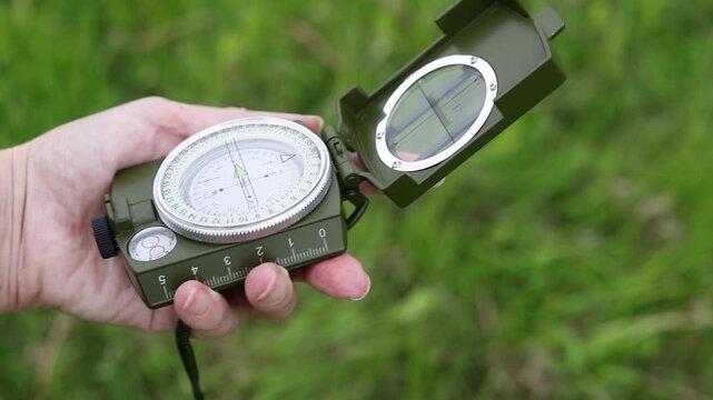 Compass in a person's hands. Person navigate the terrain using a compass. Orienteering, travel, tourism, hiking