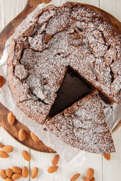 Italian torta caprese: this chocolate and almond cake is dense, rich and moist closeup on the wooden board on the table. Vertical top view from above
