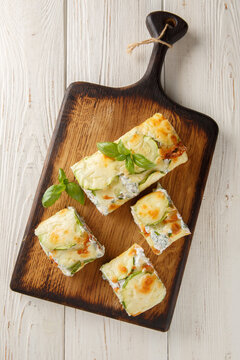 Baked Zucchini roll with cream cheese, herbs and salmon closeup on the wooden board on the table. Vertical top view from above