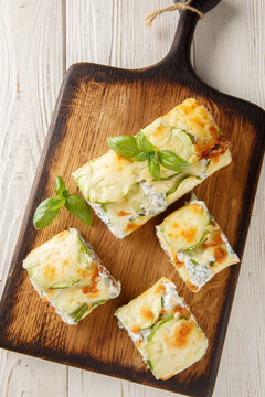 Zucchini roll with cream cheese and salmon closeup on the wooden board on the table. Vertical top view from above