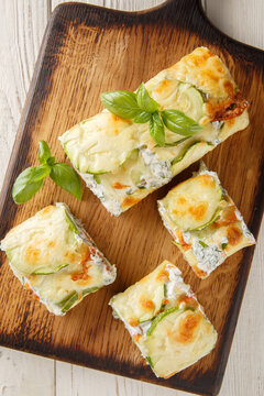 delicious roll of baked zucchini with cheese, stuffed with salmon and cream cheese, close-up on a wooden board on the table. Vertical top view from above
