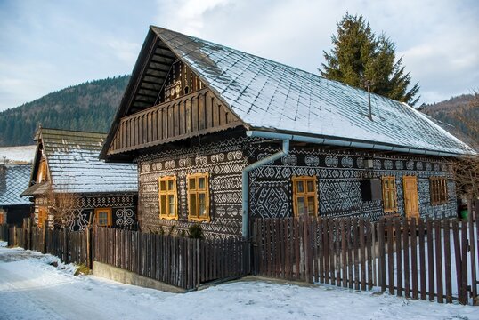 Historic wooden cottage decorated with white painted folk patterns in snowy Cicmany village, Slovakia.