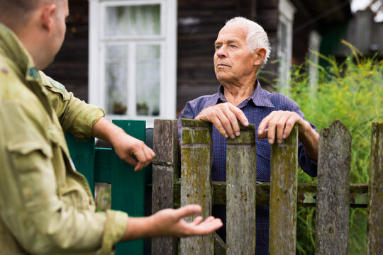 Farm neighbors talk at the border of garden plot