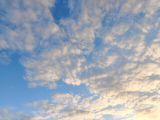 Fototapeta premium Warm sunlight illuminating scattered clouds in a blue sky 