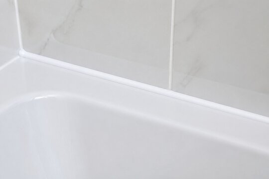 A smooth, continuous bead of white sealant along a bathtub and tile joint.
