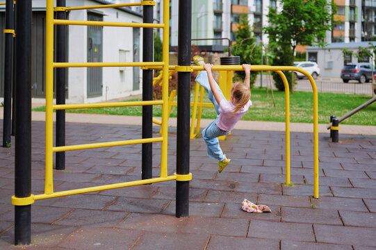 Young girl actively playing on the monkey bars at a modern urban playground