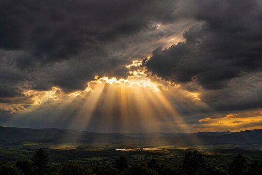 Dramatic sunbeams breaking through dark storm clouds over a landscape, cinematic lighting.