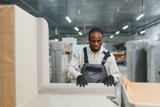 African american Furniture maker upholstering sofa in factory warehouse